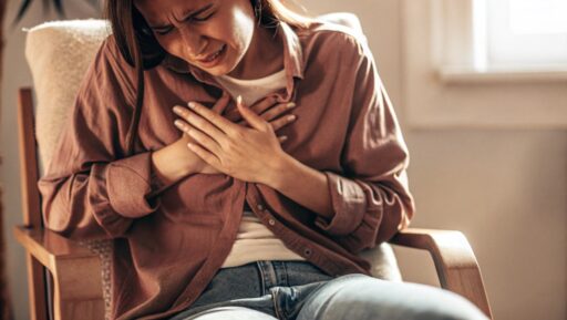 胸を押さえて苦しそうにする若い女性、心臓や血圧の不調をイメージ